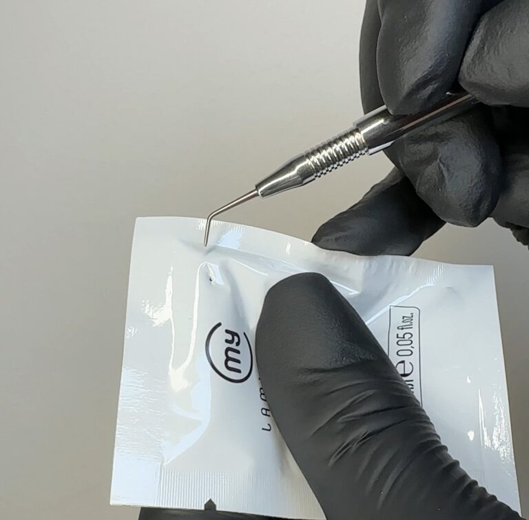 Präzise Erstellung eines kleinen Lochs in einem Lash-Lifting-Präparat-Sachet mit einem Spezialwerkzeug.